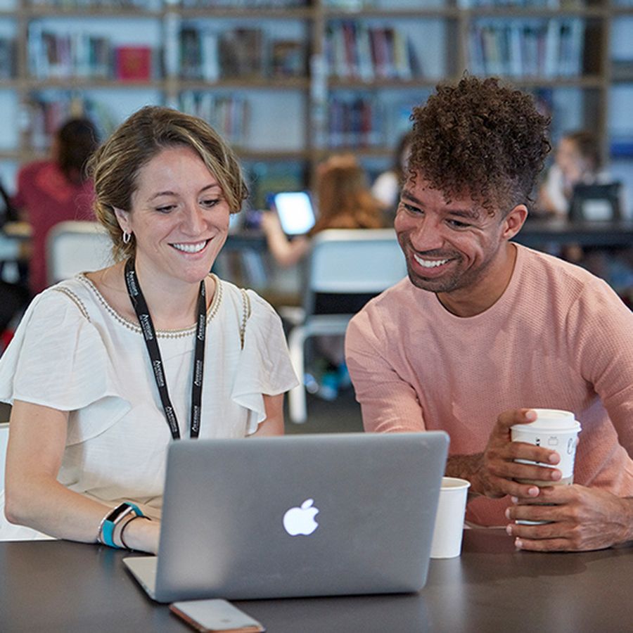 Two Avenues faculty sitting at a laptop, smiling